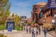 The University of Nevada at Reno campus with buildings on the right and a blue sign on the left with a capital “N” in the center