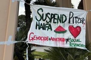 A sign reads “Suspend Pitzer Haifa” in capital letters with a picture of a watermelon and a heart.